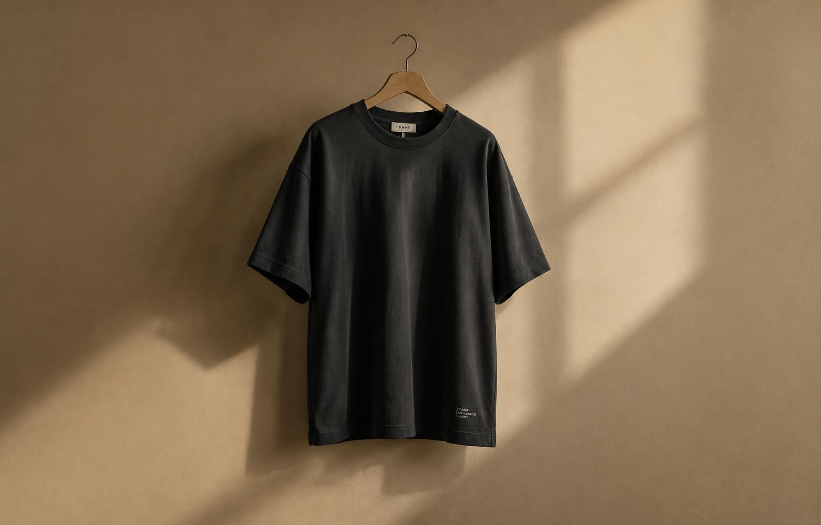 A premium heavyweight charcoal DiamondTees t-shirt on a wooden hanger in soft studio light